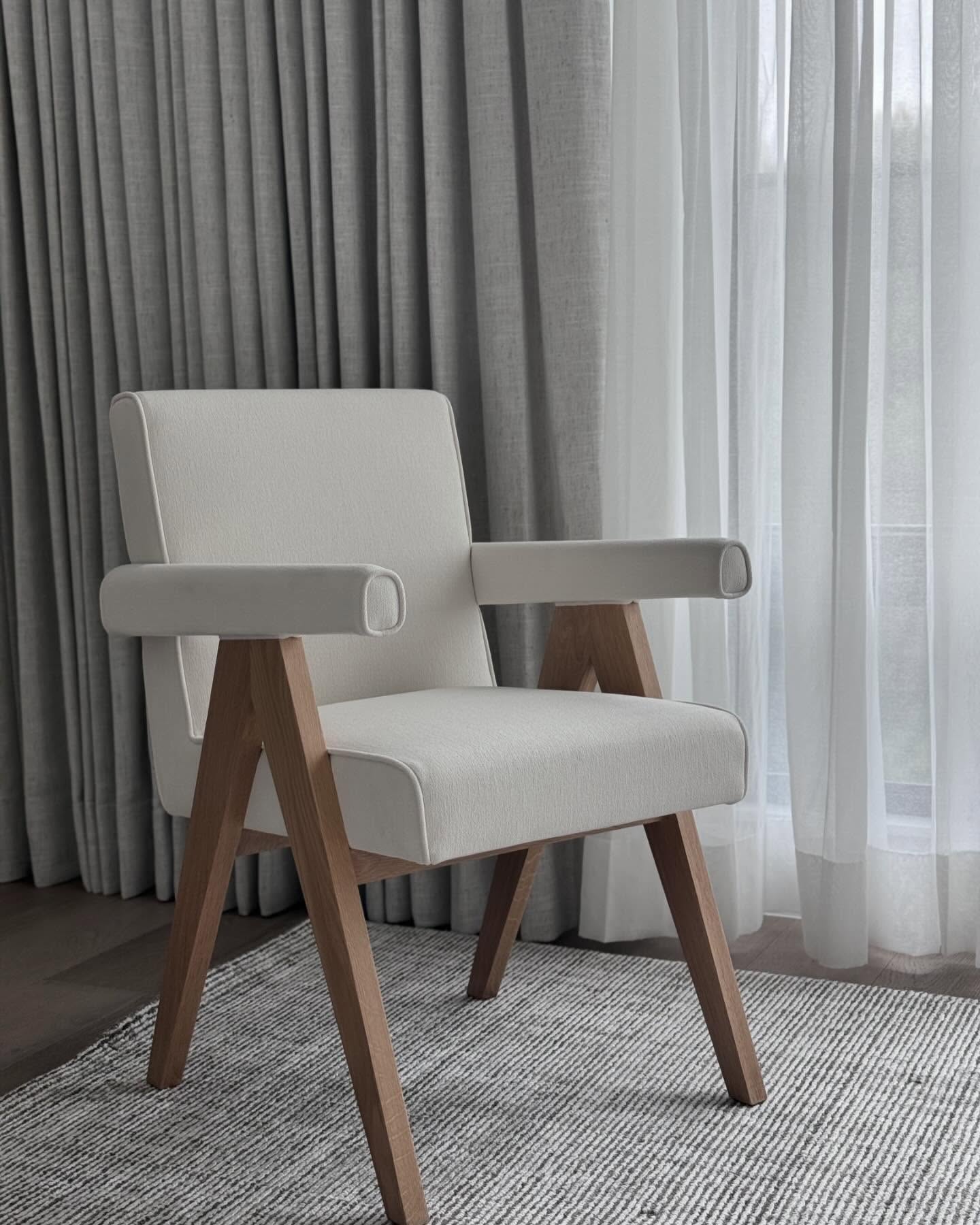 Ivory boucle armchair with white oak frame beside layered linen drapery