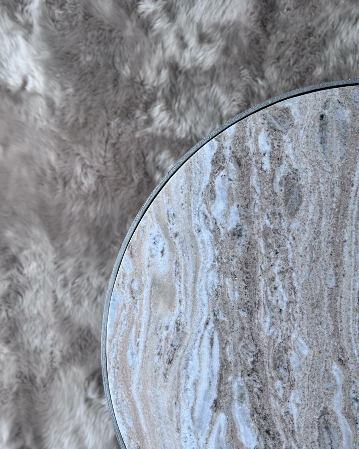 Overhead view of a round marble side table beside a chair draped in sheepskin