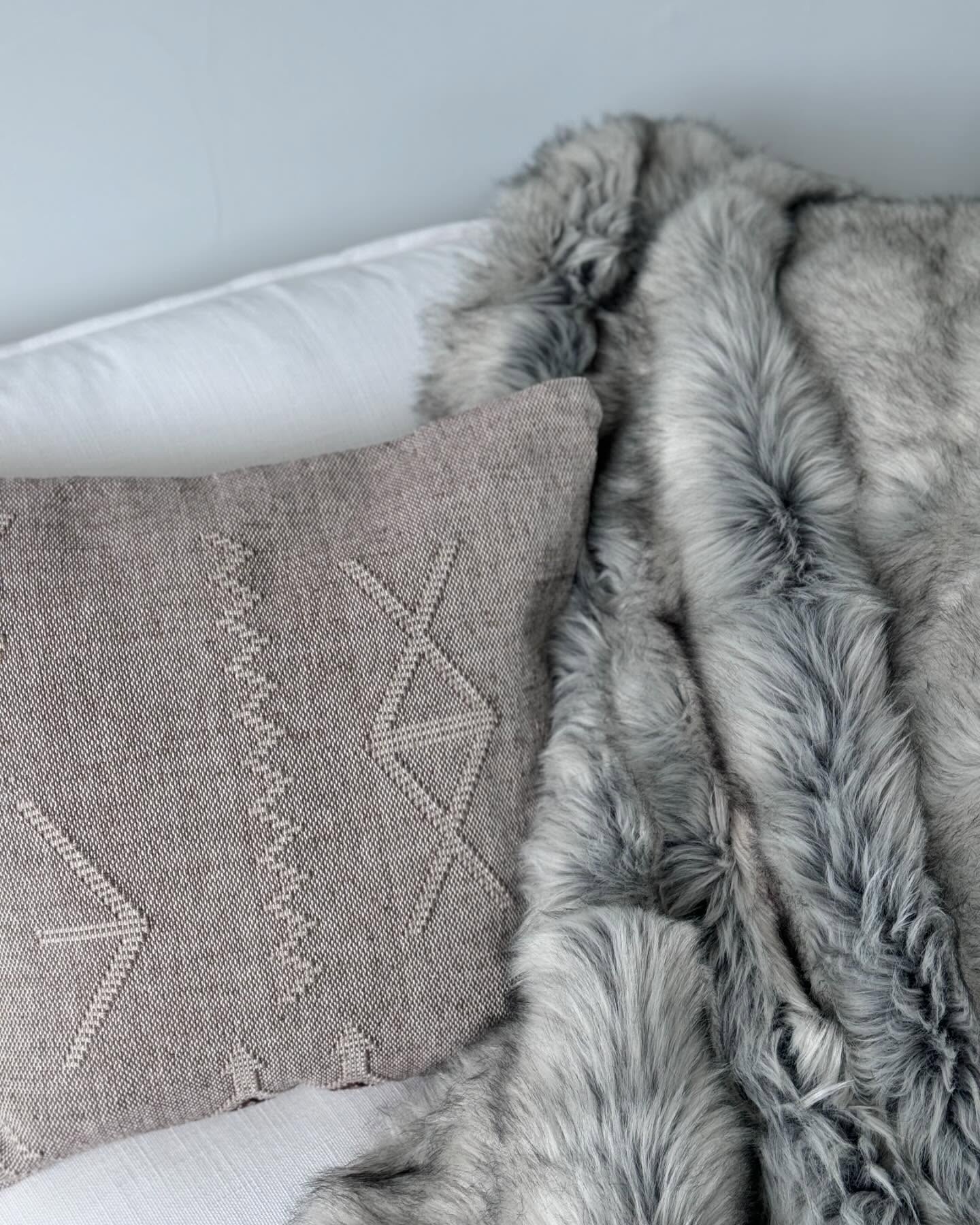 Gray shearling throw and taupe pillow on white upholstery