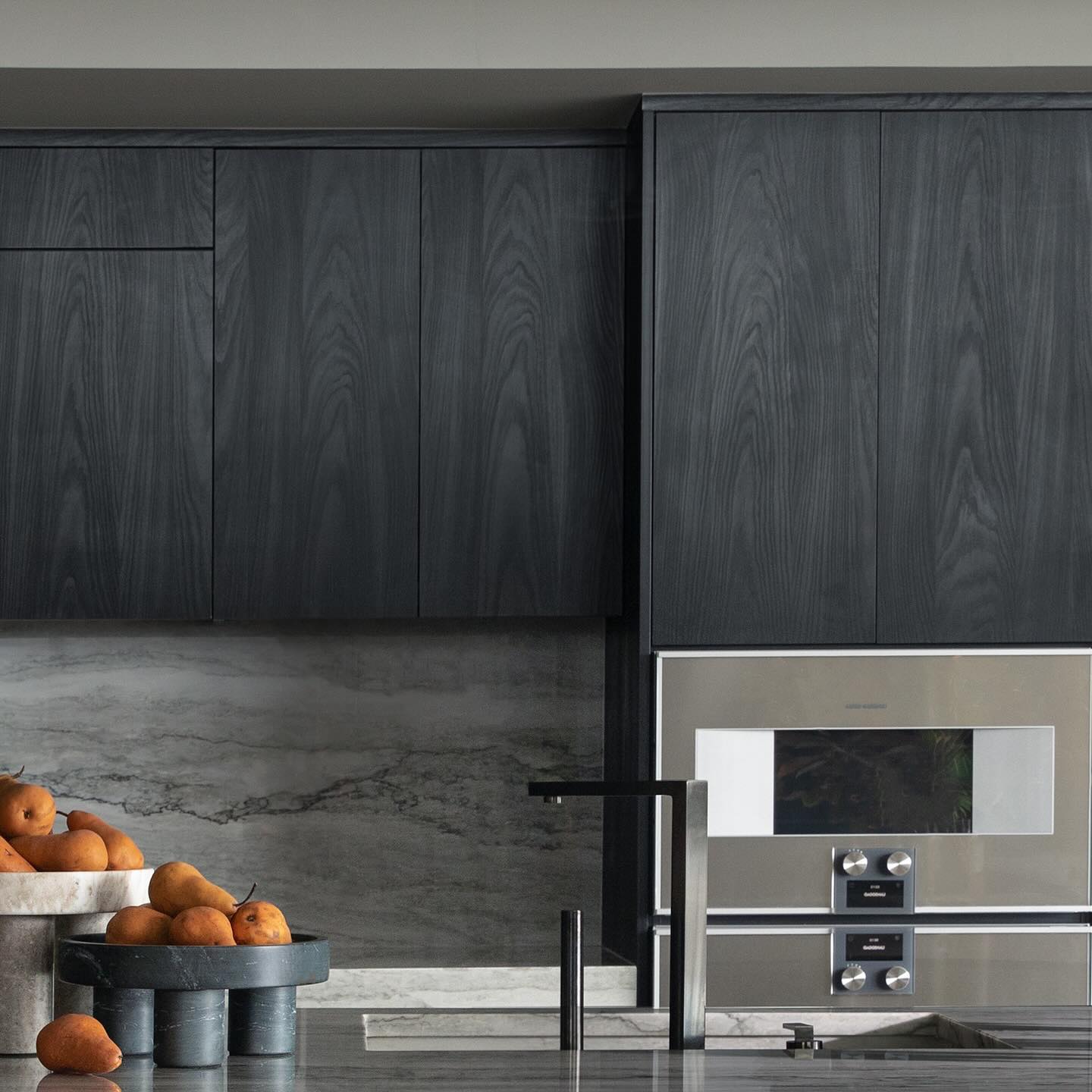 Charcoal kitchen with dramatic marble slab backsplash and integrated Gaggenau range