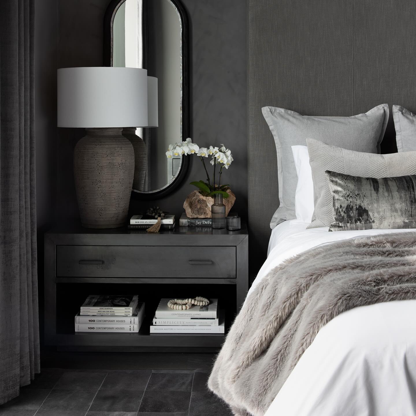 Moody charcoal bedroom vignette with layered natural textiles in low warm light