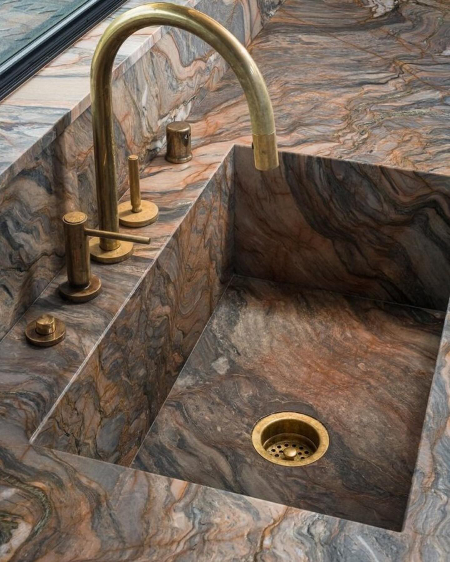 Carved quartzite sink with an aged brass faucet in warm side light