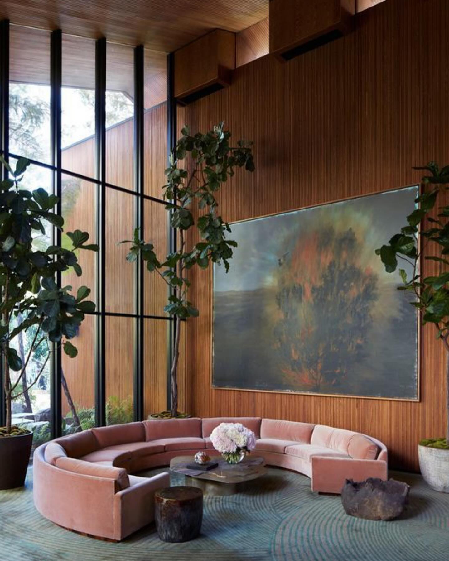 Double-height living room wrapped in vertical wood slats, with a blush curved sofa in soft natural light
