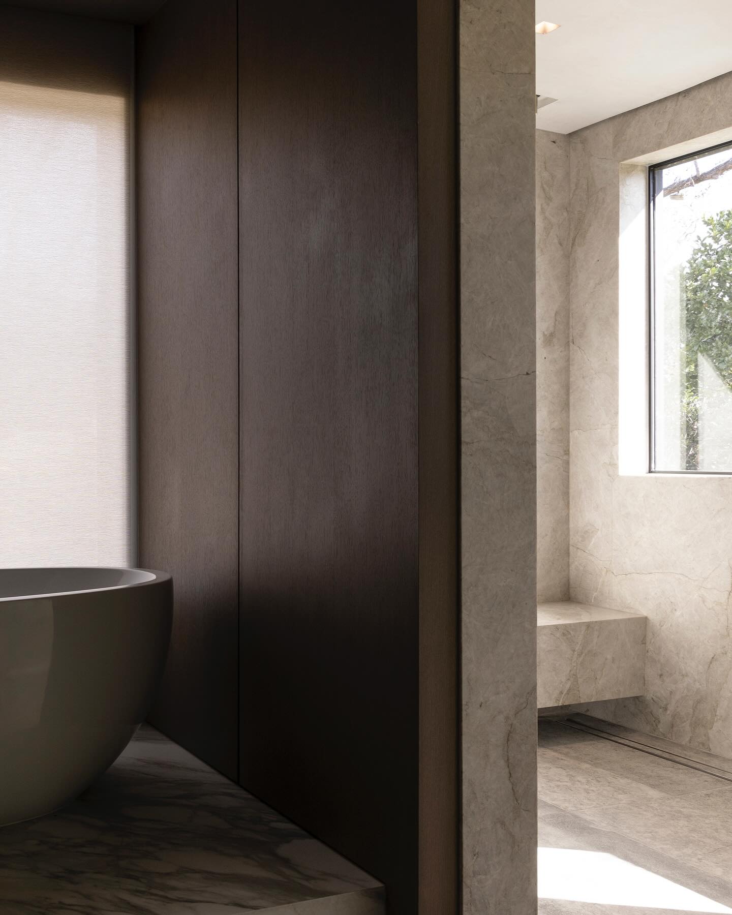 Bath vista moving from dark oak paneling into a light-filled quartzite wet room