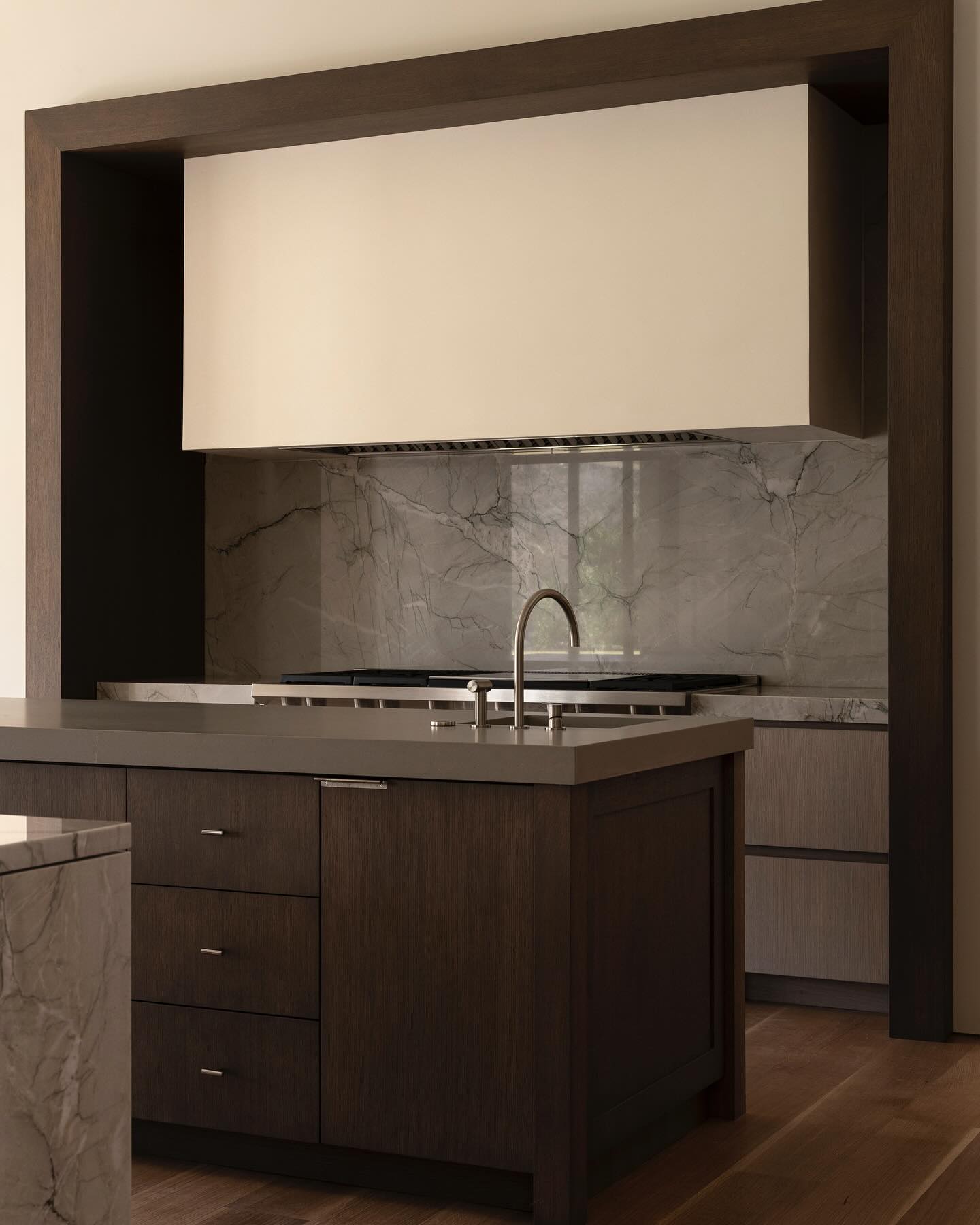 Organic-modern kitchen with plaster range hood, quartzite slab, and dark oak portal